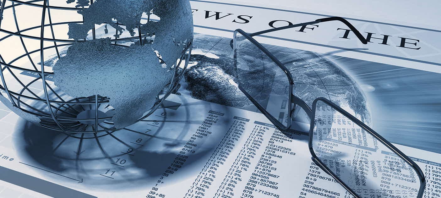 Glass globe beside a financial newspaper and reading glasses