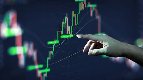 Hand pointing at a rising candlestick chart
