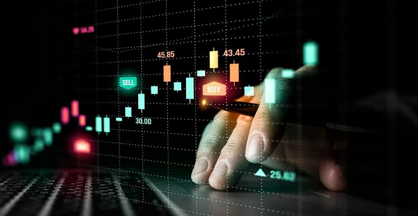 Buy and sell candlestick signals over a trader's hand on a laptop